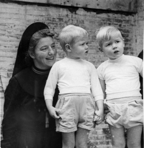 876989 Afbeelding van een Zuster Augustines, met twee jongetjes, een tweeling, op de binnenplaats van het opvanghuis ...